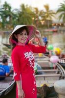 contento donna indossare ao dai vietnamita vestire, viaggiatore visitare gio bon fiume e giro turistico barca cavalcata a Hoi un antico cittadina. punto di riferimento per turista attrazioni.vietnam e sud-est viaggio concetto foto