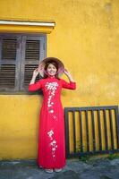 contento donna indossare ao dai vietnamita vestito e cappello, viaggiatore giro turistico a Hoi un antico cittadina nel centrale Vietnam. punto di riferimento e popolare per turista attrazioni. Vietnam e sud-est viaggio concetto foto