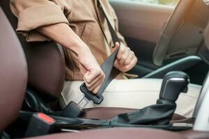 la cintura di sicurezza del conducente della donna che allaccia la cintura di sicurezza durante la seduta all'interno di un'auto e la guida su strada. concetto di sicurezza, viaggio, viaggio e trasporto foto