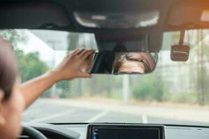 autista donna regolazione specchietto retrovisore un'auto. concetti di viaggio, viaggio e trasporto di sicurezza foto