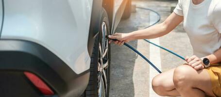 donna conducente gonfiare a mano le gomme del veicolo, controllare la pressione dell'aria e riempire l'aria sulla ruota dell'auto alla stazione di servizio. concetto di trasporto self-service, manutenzione e sicurezza foto