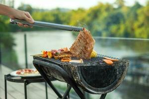 deliziosa carne alla griglia con fumo, barbecue con verdure all'aperto. concetto di barbecue, festa, stile di vita e picnic foto