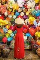 contento donna indossare ao dai vietnamita vestito con colorato lanterne, viaggiatore giro turistico a Hoi un antico cittadina nel centrale vietnam.punto di riferimento per turista attrazioni.vietnam e sud-est viaggio concetto foto