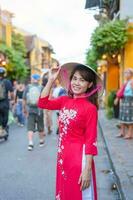 contento donna indossare ao dai vietnamita vestire, asiatico viaggiatore giro turistico a Hoi un antico cittadina nel centrale Vietnam. punto di riferimento e popolare per turista attrazioni. Vietnam e sud-est viaggio concetto foto