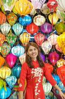 contento donna indossare ao dai vietnamita vestito con colorato lanterne, viaggiatore giro turistico a Hoi un antico cittadina nel centrale vietnam.punto di riferimento per turista attrazioni.vietnam e sud-est viaggio concetto foto