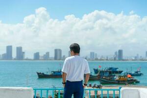 uomo viaggiatore visitare a figlio tra marina. turista con blu vestito e cappello in viaggio nel da nang città. Vietnam e sud-est Asia viaggio concetto foto