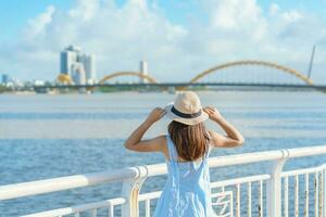 donna viaggiatore con blu vestito visitare nel da nang città. turista giro turistico il fiume Visualizza con Drago ponte. punto di riferimento e popolare per turista attrazione. Vietnam e sud-est Asia viaggio concetto foto