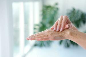 avvicinamento donna è mani con caffè massaggio macchia su Monstera sfocato sfondo. cosmetologia, mano cura, terme cosmetici, bellezza concetto. foto