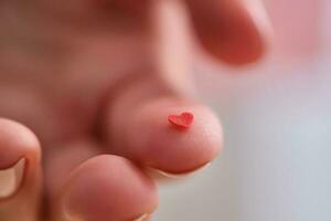 rosso cuore su il dito di un' donna di mano. concetto. foto