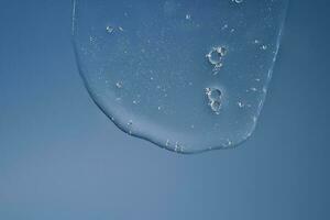 il struttura di un' gel o shampoo fluente giù su un' blu sfondo. foto