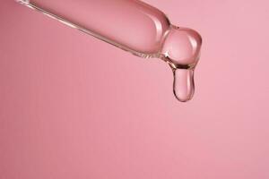 contagocce con siero o cosmetico olio su un' rosa sfondo. foto