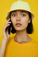 attraente donna nel un' giallo cappello gioventù stile casuale parlando su il Telefono isolato sfondo foto