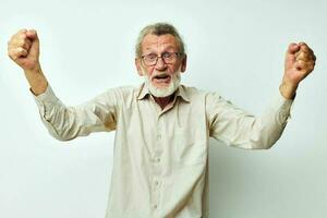 anziano uomo nel camicia con mani sollevato su emozioni leggero sfondo foto
