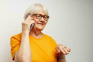 sorridente anziano donna nel casuale maglietta occhiali da sole parlando su il Telefono ritagliata Visualizza foto