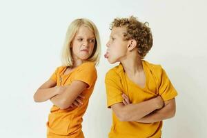 immagine di positivo ragazzo e ragazza nel giallo magliette in piedi lato di lato infanzia emozioni inalterato foto