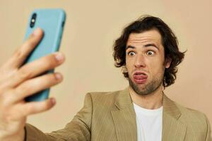 bello uomo con un' Telefono nel mano beige completo da uomo elegante stile stile di vita inalterato foto