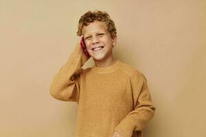 poco ragazzo nel un' maglione parlando su il Telefono foto