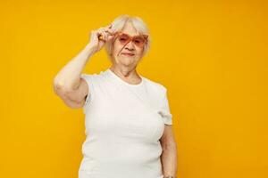 ritratto di un vecchio amichevole donna nel casuale maglietta e bicchieri avvicinamento emozioni foto