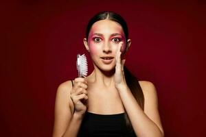 giovane bellissimo donna con un' pettine nel mano luminosa trucco in posa moda emozioni rosa sfondo inalterato foto