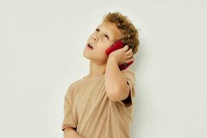 allegro carino ragazzo con Telefono nel mani in posa tecnologia foto