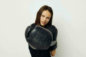 giovane donna nel boxe guanti punch nel nero pantaloni e un' maglietta isolato sfondo foto