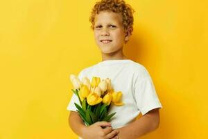 carino poco ragazzo Tenere un' mazzo di fiori un' regalo giallo sfondo inalterato foto