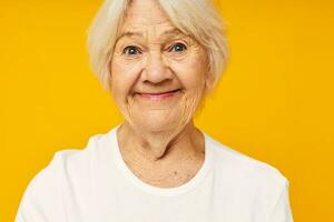 sorridente anziano donna nel bianca maglietta in posa divertimento isolato sfondo foto