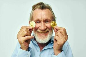 ritratto anziano uomo nel un' blu camicia bitcoin su il viso leggero sfondo foto