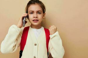 bella giovane ragazza parlando su il Telefono con un' zaino infanzia inalterato foto