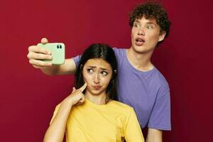 un' giovane coppia nel colorato magliette con un' Telefono isolato sfondo foto