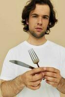 attraente uomo nel un' bianca maglietta con coltello con forchetta isolato sfondo foto