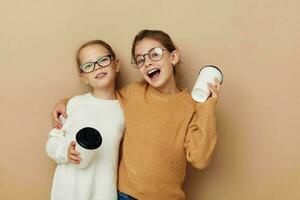 Due poco ragazze con monouso bicchieri nel loro mani foto