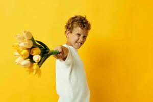 poco ragazzo Tenere un' mazzo di fiori un' regalo giallo sfondo inalterato foto