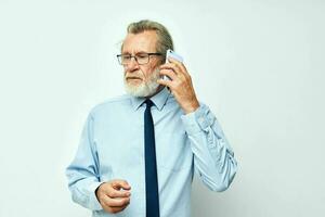 anziano dai capelli grigi uomo nel un' camicia con un' cravatta parlando su il Telefono ritagliata Visualizza foto