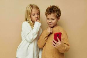 poco ragazzo e ragazza con un' rosso Telefono insieme tecnologie isolato sfondo foto