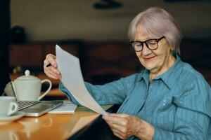 anziano donna Lavorando nel davanti di il computer portatile tenere sotto controllo seduta stile di vita inalterato foto