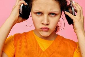 divertente ragazza ascoltando per musica con cuffie arancia maglione emozioni divertimento rosa sfondo inalterato foto