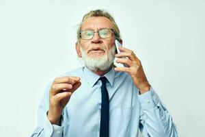 anziano dai capelli grigi uomo nel un' camicia con un' cravatta parlando su il Telefono ritagliata Visualizza foto