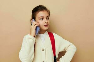 bella giovane ragazza parlando su il Telefono con un' zaino infanzia inalterato foto