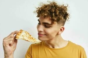 attraente uomo nel un' giallo maglietta mangiare Pizza stile di vita inalterato foto