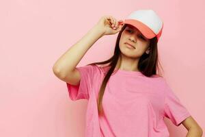 allegro giovane ragazza con un' berretto su sua testa nel un' rosa maglietta foto