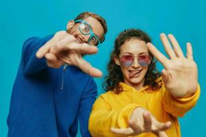 un' donna e un' uomo divertimento coppia avviamento e mostrando segni con loro mani sorridente allegramente, su un' blu sfondo, il concetto di un' vero relazione nel un' famiglia. foto