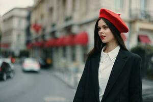 moda donna ritratto bellezza in piedi su il strada nel davanti di il città nel elegante Abiti con rosso labbra e rosso berretto, viaggiare, cinematico colore, retrò Vintage ▾ stile, urbano moda stile di vita. foto