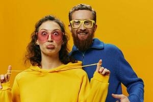 uomo e donna coppia sorridente allegramente e storto con occhiali, su giallo sfondo, simboli segni e mano gesti, famiglia sparare, Novelli sposi. foto