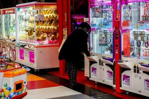 osaka, Giappone, 2019- giapponese ragazza giocando bambole Consiglio dei ministri catture macchina intensamente nel gioco negozio. bambole Consiglio dei ministri catture è un' monete operato divertimento macchina, popolare nel Giappone e Asia. foto
