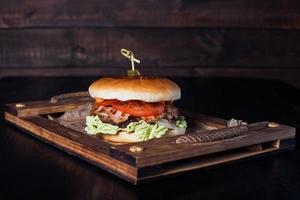 cheeseburger su un vassoio di legno in un ristorante, su uno sfondo scuro