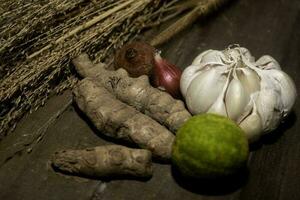 aglio e rosso cipolla, unione, Curcuma , lime dentro un' intrecciata bambù scatola su di legno sfondo foto