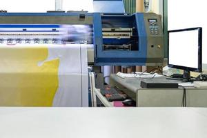 grande stampante a getto d'inchiostro che lavora su banner in vinile con schermo di computer