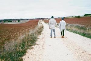 coppia di giovani millennial in piedi e tenendosi per mano contemplando lo skyline in un viaggio avventuroso su un sentiero di campagna all'aperto foto