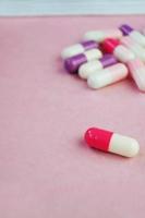 una macro dettagliata di pillole e capsule da una maschera medica con sfondo rosa foto